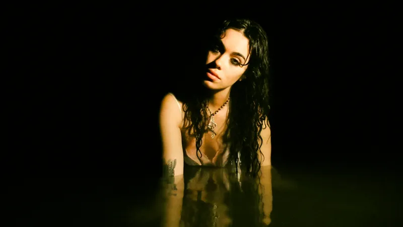 Woman with wet hair emerging from dark water, lit from one side