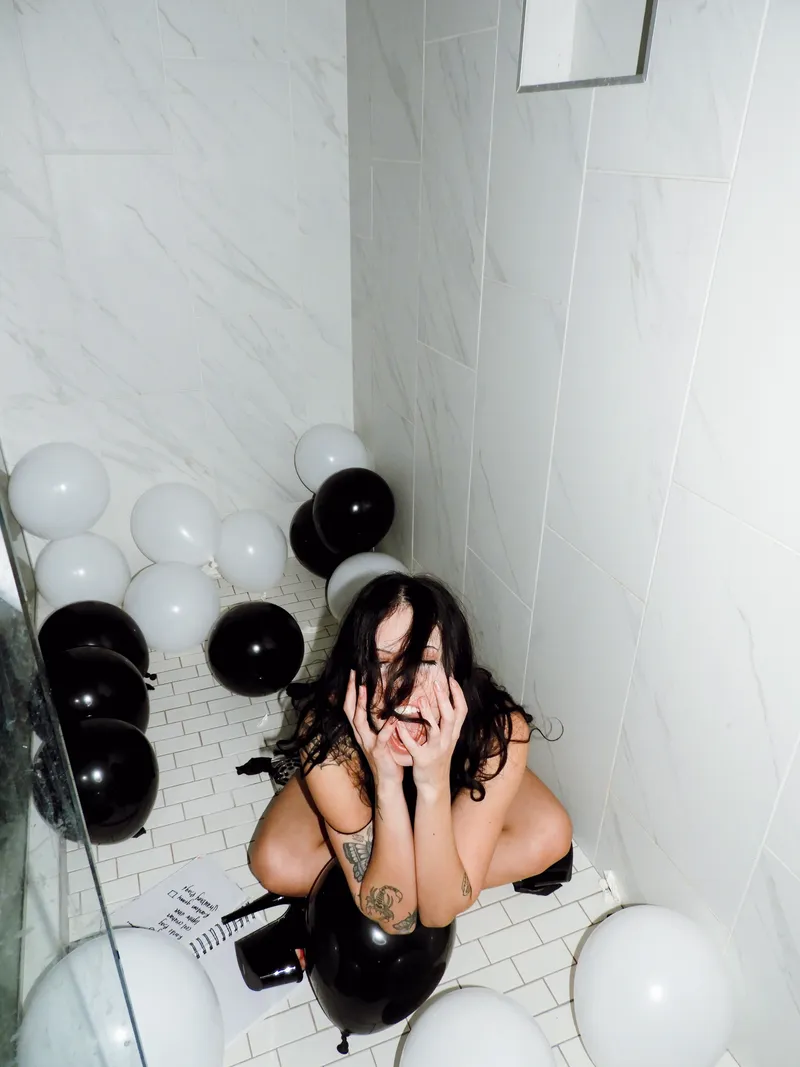 Woman laughing in a shower full of black and white balloons
